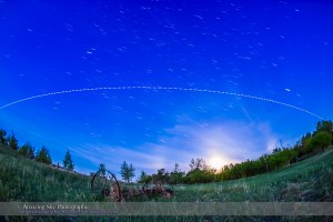 A pass of the International Space Station in the brightening twilight of dawn, on the morning of June 1, 2015, with the gibbous Moon setting to the southwest at right. The view is looking south, with the ISS travelling from right (west) to left (southeast) over several minutes. This was the last pass of a 4-pass night, May 31/June 1, starting at 3:55 am MDT this morning.  This is a composite stack of 144 exposures, each 2 seconds at f/2.8 with the 15mm full-frame fish-eye and ISO 3200 with the Canon 6D. The gaps are from the 1-second interval between exposures. The length of the trails and gaps reflects the changing apparent speed of the ISS as it approaches, passes closest, then flies away.  I stacked the exposures with the Advanced Stacker Actions from StarCIrcleAcademy.com, using the Lighten mode. The ground comes from a Mean blend of just 8 of the exposures to prevent shadows from blurring but to smooth noise.