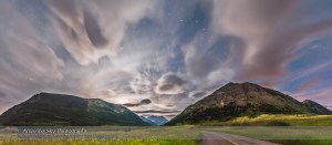 A panorama of the flower-filled Blakiston Valley on a moody moonlit cloudy night at Waterton Lakes National Park, June 24, 2015. The Big Dipper is at upper right, with its handle pointing to Arcturus at left of centre. Spica is at far left. A subtle halo surrounds the first quarter Moon which has just set behind Crandell Mountain at left.  This is a 9-segment panorama with the Nikon D750 and 24mm lens, mounted portrait, and stitched with Photoshop using spherical geometry and corrected with Wide Angle Adaptive Lens Correction to straighten the scene. Liberal use of Highlight and Shadow recovery in ACR and Shadows and Highlights in PS brought out the flower-filled foreground while retaining detail in the bright sky. Each segment was 30 seconds at f/2.8 and ISO 1600.