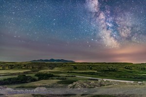 The summer Milky Way with a meteor streaking at centre as a bonus. An aurora to the north off frame is lighting the foreground with a green glow. Haze and forest fire smoke obscure the horizon. I shot this at the Battle Scene viewpoint at Writing-on-Stone Provincial Park, in southern Alberta. Sagittarius and the galactic centre is on the horizon at left of centre. Capricornus is amid the haze at left of centre. On the horizon are the Sweetgrass Hills in Montana. The Milk River winds below amid the sandstone formations that are home to historic First Nations petroglyphs.  This is a single 30-second exposure with the Nikon D750 at ISO 3200 and Sigma 24mm Art lens at f/2, taken as part of a time-lapse sequence.