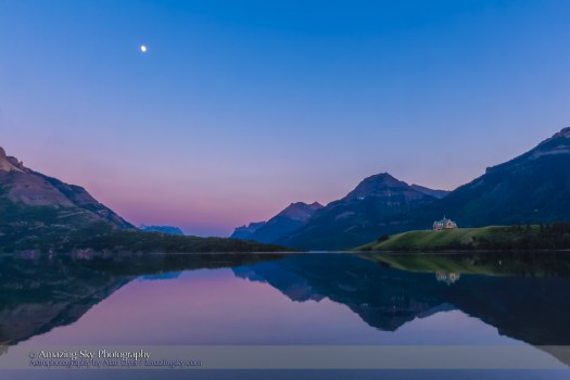 The waxing gibbous Moon over Upper Waterton Lake in Waterton Lakes National Park, Alberta with the iconic Prince of Wales Hotel in the distance, on a calm evening with still waters, rare in Waterton. This is an HDR stack of 3 exposures with the Canon 60Da and 16-35mm lens, shot from Driftwood Beach.