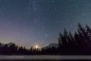 A pair of Perseid meteors shoot at left in the late night sky at the Upper Bankhead parking lot in Banff National Park. The  waning crescent Moon is just rising above the trees. A faint Perseid is at right, while a satellite trail goes from left to right as well.  Taken the night of Saturday, August 11 into the wee hours of Sunday, August 12, 2012 with the Canon 7D and 10-22mm Canon lens. This is a stack of two exposures, one for each meteor, each for 60 seconds at ISO 1250 and f/4. The stars are trailed slightly due to the two-minute exposure time in total.