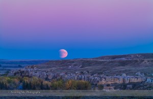 The Full Moon rises in partial eclipse over the sandstone formations of Writing-on-Stone Provincial Park in southern Alberta, on the evening of September 27, 2015. This was the night of a total lunar eclipse, which was in progress in its initial partial phase as the Moon rose this night. The blue band on the horizon containing the Moon is the shadow of Earth on our atmosphere, while the dark bite taken out of the lunar disk is the shadow of Earth on the Moon. The pink band above is the Belt of Venus. This is a two-image panorama stitched to extend the scene vertically to take in more sky and ground than one frame could accommodate. Both shot with the 200mm lens and 1.4x extender, on the Canon 5DMkII.
