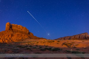 The total lunar eclipse of April 4, 2015 taken from near Tear Drop Arch, in western Monument Valley, Utah. I shot the totality images at 6:01 a.m. MDT, during mid-totality during the very short 4 minutes of totality. The mid-totality image is a composite of 2 exposures: 30 seconds at f/2.8 and ISO 1600 for the sky and landscape, with the sky brightening blue from dawn twilight, and 1.5 seconds at f/5.6 and ISO 400 for the disk of the Moon itself. Also, layered in are 26 short exposures for the partial phases, most being 1/125th sec at f/8 and ISO 400, with ones closer to totality being longer, of varying durations. All are with the 24mm lens and Canon 6D on a static tripod, with the camera not moved through the entire sequence. The short duration of totality at this eclipse lent itself to a sequence with one total phase image flanked by partial phases. The rocks are illuminated by lights from the community - light pollution but photogenic in this case - and partly from dawn glow in the east.