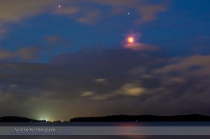 The total eclipse of the Moon, April 15, 2014 local time just after sunset from Australia, seen from Shingle Splitter's Point overlooking Lake Macquarie on the Central Coast of New South Wales, Australia. It was fortunate that we saw this eclipse at all as the sky was very cloudy and at times it was actually raining on us. But about 6 pm the Moon appeared as totality was ending. The Moon appears below Spica and below right of Mars. The lake has a red glitter path from the eclipsed Moon. This is an 8-second exposure at f/2.8 with the 50mm lens on the Canon 60Da at ISO 800.