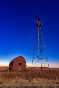 Mars, Venus and Jupiter (in that order from top to bottom) in a triangle, in conjunction, at an old farmstead near Vulcan, Alberta, in the morning twilight, October 28, 2015. Illumination is from the nearly Full Hunter’s Moon in the west. The trio of planets were in Leo in a fine conjunction not to be repeated until November 21, 2111. Almost all of Leo is visible here, with Regulus, the constellation’s brightest star, just to the right of the windmill blades at top. This is a stack of 6 exposures for the ground, mean combined to smooth noise, and one exposure for the sky, all  10 seconds at f/4 and ISO 800 with the Canon 6D and Canon 24mm lens.