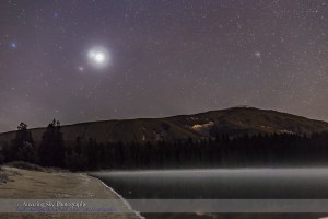 Brilliant Venus, in conjunction with dimmer Jupiter above, and with even dimmer Mars below, at left here, on the morning of October 25, 2015 when Venus and Jupiter were only 1° apart.  I shot this from Lake Annette in Jasper National Park before the sky started to brighten with dawn twilight. High haze in the sky adds the glows around the stars and planets, in particular the colored halo around Venus. The mountain is the Watchtower. The site is used as the main star party location for the annual Jasper Dark Sky Festival. This is a 30-second exposure at f/2.8 with the 35mm lens and as ISO 1600 with the Canon 6D.