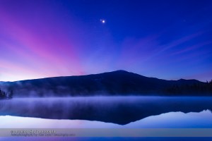 The conjunction of Venus (brightest), Jupiter (above Venus) and Mars (dimmer below Venus & Jupiter) looking east in the morning twilight on October 25, 2015, as seen from the west shore of Lake Annette, in Jasper National Park, Alberta. The mountain is the Watchtower. Morning mist covers the lake waters. Haze in the sky adds the natural glows around the planets — no filters were empolyed here. This is a layered stack of 4 images: 10, 5, 2.5 and 1.3-second exposures, with the longer exposure for the ground and the shorter exposures adding the sky to maintain tonal balance between the dark ground and bright sky. All with the 24mm lens and Canon 6D at ISO 400. It was not possible to capture the reflection of the planets in the water as they were too high in the sky.